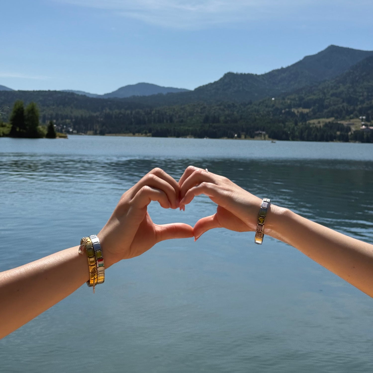 Two hands reaching towards each other with a scenic background of water and sky.